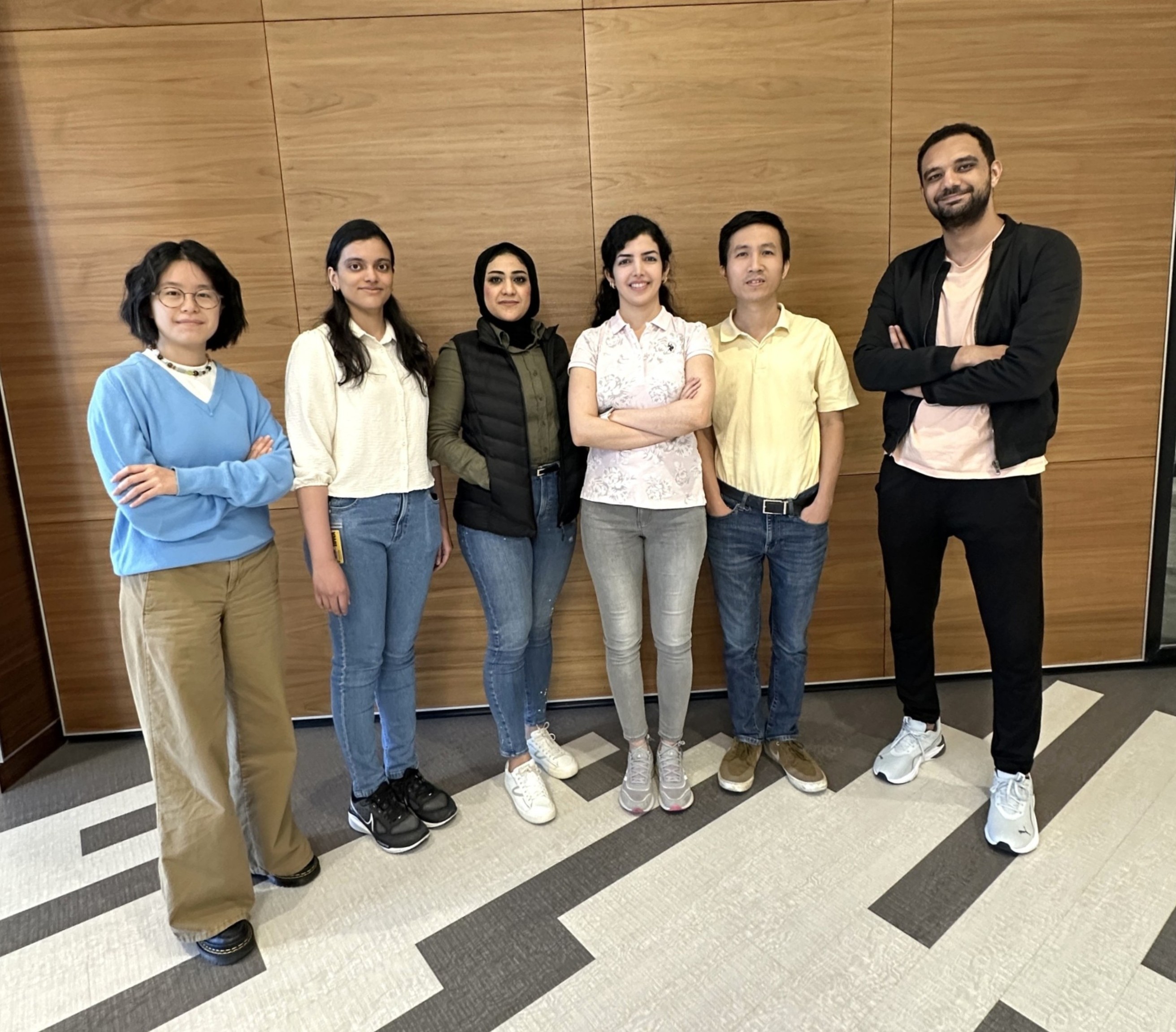 Six 2025-26 University of Iowa College of Pharmacy American Association of Pharmaceutical Scientists student chapter officers standing in a line against a wood-paneled wall in an office setting, smiling at the camera in business casual attire. 