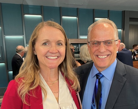 A chest-up photo of Kelly Kent and Randy McDonough standing together at an event. There is a bar and people in the background.