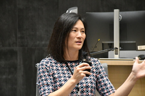  University of Iowa faculty member and PPS DEO Mary Schroeder speaks into a handheld microphone while seated at an the 2024 MSAP conference, gesturing with one hand. A computer monitor and presentation equipment are visible behind her. 