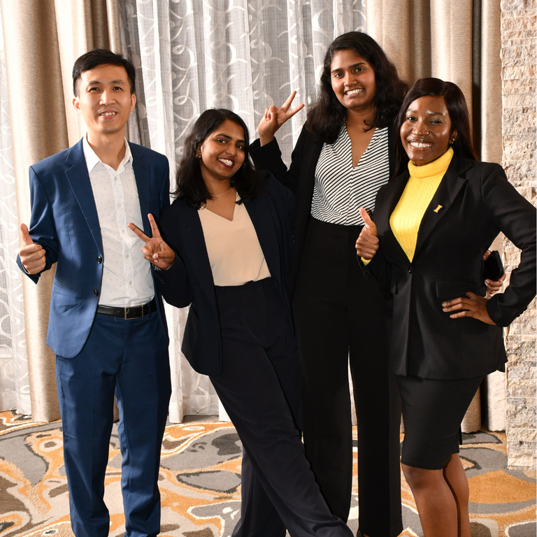Four students post at a reception during a professional conference.