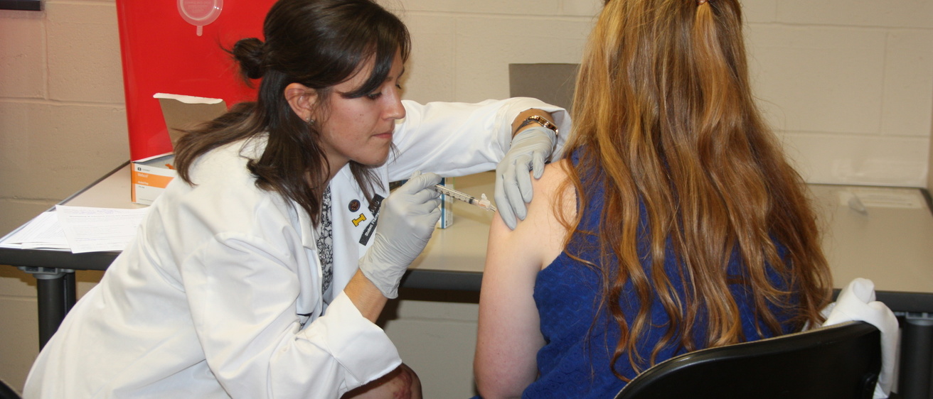 Student pharmacist administers a flu vaccination during a clinic.