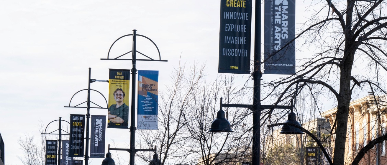 Photo of streetlamps with banners on both sides. They say "Dare to Create Innovate Explore Imagine Discover" with different verbs highlighted.