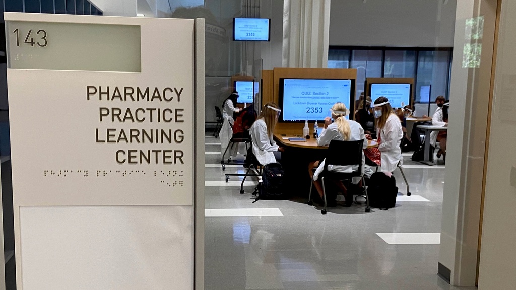 sign of the Pharmacy Practice Learning Center (PPLC), with students working at tables in the background